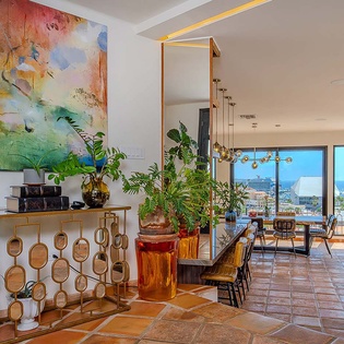 Step into a light-filled space where art and nature blend seamlessly. Lush greenery and coastal views through expansive glass doors invite relaxation and connection to the surrounding beauty.