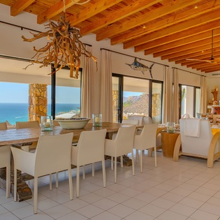 Your open-concept dining space flows seamlessly into the living area, framed by stunning sea views through floor-to-ceiling windows.