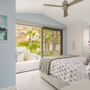 Wake up in this serene bedroom where tropical views greet you through expansive windows, complemented by soft linens and modern comfort.