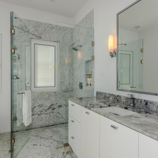 Indulge in your private spa-like bathroom featuring stunning marble surfaces, a spacious glass shower, and elegant lighting for ultimate relaxation.