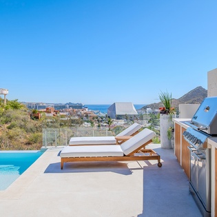 Stunning rooftop terrace with infinity pool, BBQ station, and panoramic ocean views overlooking the coastal landscape.