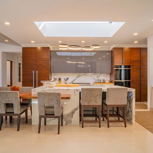This stunning kitchen invites you to gather and create memories together. Warm wood cabinetry frames gleaming marble countertops, while a central island offers space for meals and conversation beneath modern lighting.