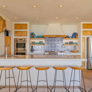 Your fully equipped gourmet kitchen features stunning blue tile backsplash, spacious island with bar seating, and high-end appliances for memorable meal prep.