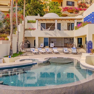 Stunning hillside villa with tropical gardens, private pool featuring integrated spa seating, and multiple terraces overlooking lush landscaping. Blue-tiled accents and a hammock-draped balcony add coastal charm to this secluded retreat.