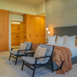 Unwind in your stylish bedroom featuring warm wood accents, pendant lighting, and comfortable seating where you can relax after exploring.