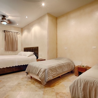 A spacious bedroom with three comfortable beds invites your group to unwind after a day of adventure. Warm lighting, ceiling fan, and crisp linens create a restful sanctuary.
