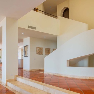 You'll love the unique multi-level design and soaring open spaces that make this home feel both grand and inviting. Warm terracotta tile flows throughout, complemented by smooth white architectural lines and soft, natural light.