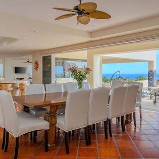 Gather around this generous dining table where the ocean stretches endlessly before you, framing every meal with breathtaking coastal views. The open design flows seamlessly to your patio, inviting you to savor both indoor comfort and outdoor beauty.