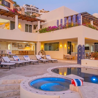 This hillside villa offers a private pool, hot tub, and multiple outdoor lounging areas. Vibrant bougainvillea cascades over terraces, while the open-air design invites you to relax poolside or retreat to shaded seating under the pergola.