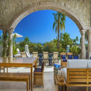 Your tropical terrace sanctuary awaits with elegant stone arches framing endless blue skies and swaying palms for perfect relaxation.