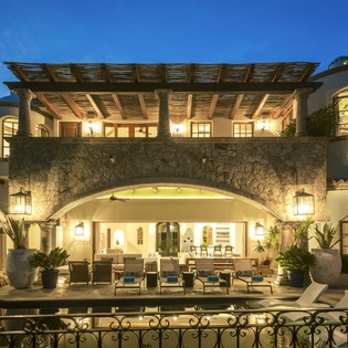 Stunning Mediterranean villa showcases elegant stone archways and warm evening lighting against a deep blue twilight sky.