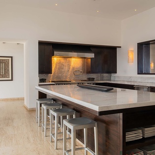 Modern kitchen with sleek dark cabinetry, marble countertops, and professional-grade appliances invites you to prepare memorable meals during your stay.