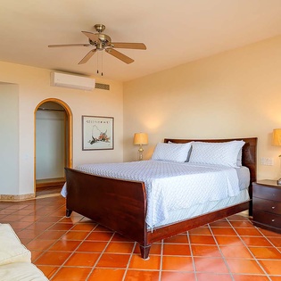 Unwind in your spacious bedroom with warm terracotta tile floors, a plush bed, and gentle ceiling fan to keep you comfortable.