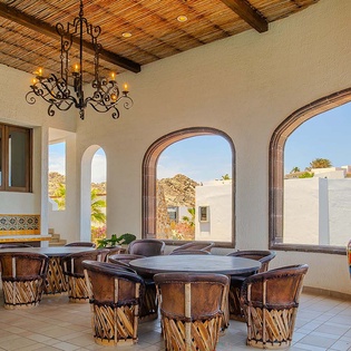 Gather around handcrafted tables under glowing chandeliers while sunlight streams through arched windows, revealing desert views and vibrant local art that welcomes you to this warm communal space.