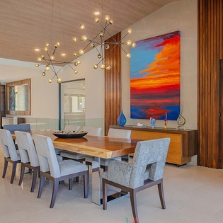 Gather around this stunning dining space where contemporary design meets warm wood tones, illuminated by a striking modern chandelier and vibrant artwork that sets the perfect mood for your meals.