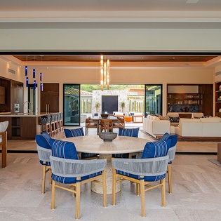 Gather around the elegant dining table while the open design flows seamlessly into the kitchen and living spaces, with natural light streaming through the glass doors to your private outdoor terrace.