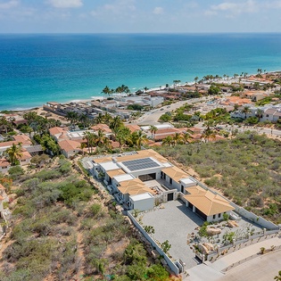 Aerial view of the property nestled in a coastal neighborhood, with pristine turquoise waters and sandy beaches just moments away.