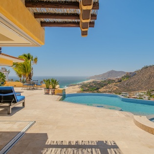 Expansive terrace with infinity pool showcasing dramatic mountain and ocean views in a stunning desert coastal setting.