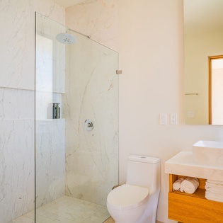 Step into your sleek marble bathroom with rainfall shower, vessel sink, and fluffy towels waiting for your arrival.