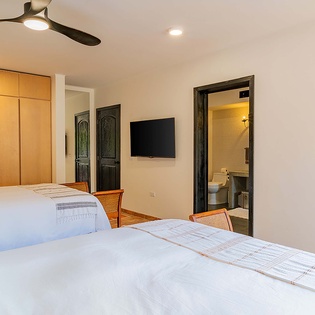 Relax in your spacious bedroom with crisp white linens, modern ceiling fan, flat-screen TV, and private ensuite bathroom—your perfect retreat after a day of adventure.