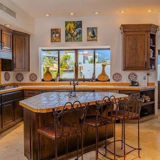 Imagine preparing your favorite meals in this bright, fully-equipped kitchen featuring handcrafted tile countertops, custom wood cabinetry, and a welcoming island where you can gather with loved ones.