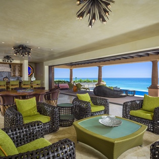 Relax in your open-concept living space where vibrant green seating meets stunning ocean views through expansive windows.