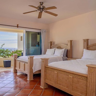 Your serene retreat features twin beds with crisp linens and opens to a private terrace where ocean breezes and coastal views create your perfect escape.