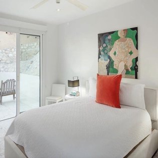 Wake up in your serene white bedroom, where vibrant art meets modern comfort and glass doors open to your private garden sanctuary.