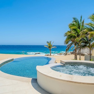 Soak in your private hot tub steps from the pool, with swaying palms, golden sand, and endless turquoise ocean stretching before you—pure beachfront bliss.
