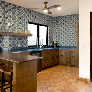 Your fully equipped kitchen features stunning tile backsplash, breakfast bar seating, and opens to a peaceful balcony with garden views.
