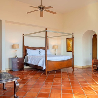 Your spacious retreat features a stunning four-poster bed, warm terracotta tile floors, and charming architectural details that create an elegant yet welcoming atmosphere for your stay.