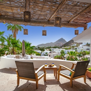 Your private terrace invites relaxation with comfortable seating overlooking tropical palms and mountain views—perfect for morning coffee or evening cocktails.