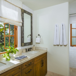 Refresh in your elegant bathroom with natural light streaming through tropical windows, creating a serene spa-like retreat.