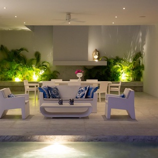 Unwind in your elegant outdoor living space where modern white furniture meets lush tropical greenery, creating the perfect evening retreat.