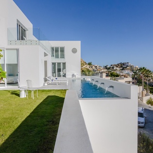 Modern villa with private pool, manicured lawn, and stunning Mediterranean coastal views.