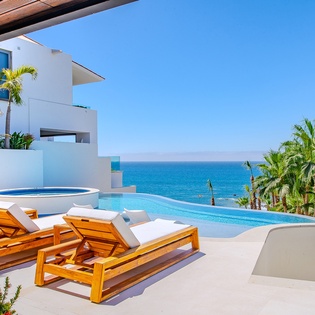 Lounge poolside with ocean views stretching to the horizon, surrounded by swaying palms in your tropical paradise.