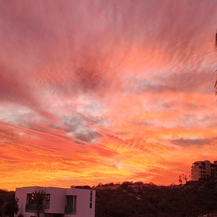 Spectacular sunset paints the sky in brilliant coral and orange hues above the tropical property location.