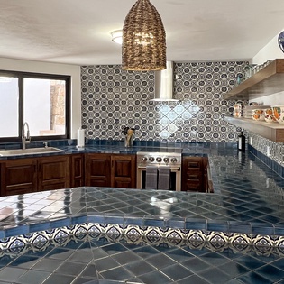 You'll love cooking in this stunning kitchen with handcrafted tiles, rich wood cabinets, and spacious countertops perfect for preparing meals.