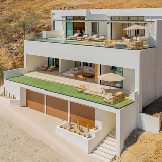 Modern multi-level property nestled in natural desert landscape with contemporary white architecture and expansive outdoor terraces.