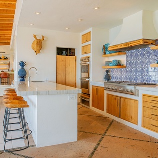 Your gourmet kitchen features warm wood cabinetry, marble countertops, and a stunning blue mosaic backsplash perfect for culinary adventures.