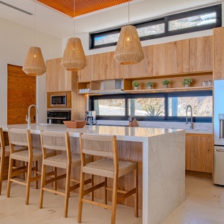 Your modern kitchen awaits with warm wood accents, sleek marble island, and natural light streaming through panoramic windows.