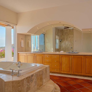 Sunlight streams across your spacious bathroom, where a deep soaking tub overlooks vibrant gardens and ocean views, inviting you to unwind in luxury.