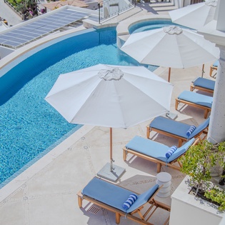 Unwind beside the sparkling blue pool with comfortable loungers and umbrellas for perfect poolside relaxation.