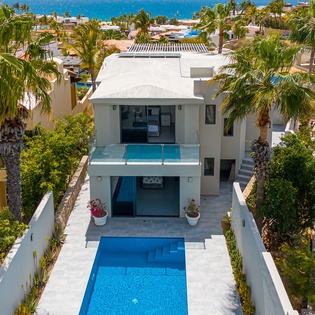 Modern tropical villa with private pool nestled among palms, just steps from pristine Caribbean waters.