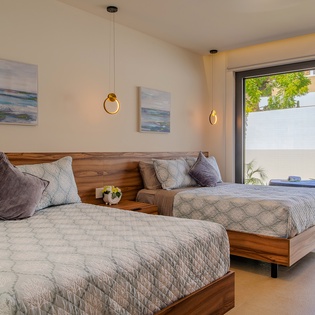 Drift into dreams on plush twin beds with stunning modern design, warm wood accents, and peaceful garden views through expansive windows.