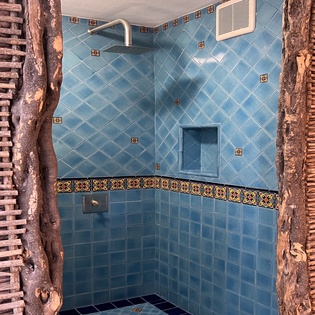 Step into your private shower adorned with beautiful blue Mexican tiles and rustic wood accents for an authentic retreat experience.