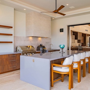 Your open-air kitchen invites effortless entertaining, with a sleek island and built-in grill ready for memorable meals under warm breezes and tropical skies.