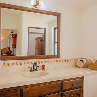 Step into your bright, airy bathroom with charming coastal tile accents and a large wood-framed mirror. Fresh towels and a well-equipped vanity await your arrival.