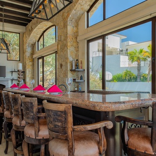 Gather around your granite breakfast bar with panoramic windows showcasing tropical palms, creating the perfect morning coffee spot in this airy open space.