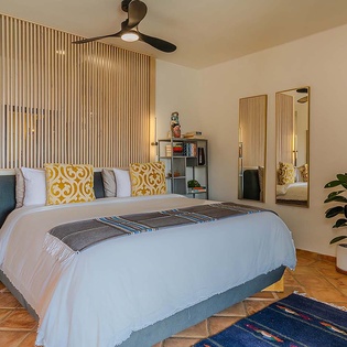 Step into your serene retreat featuring a plush king bed, stylish mid-century furnishings, and breezy ceiling fan overhead—perfect for unwinding after a day of adventure.